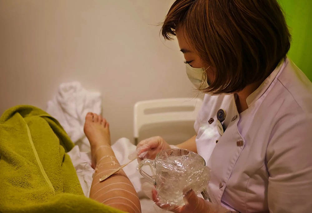 En kvinna applicerar vax på en annan kvinnas ben